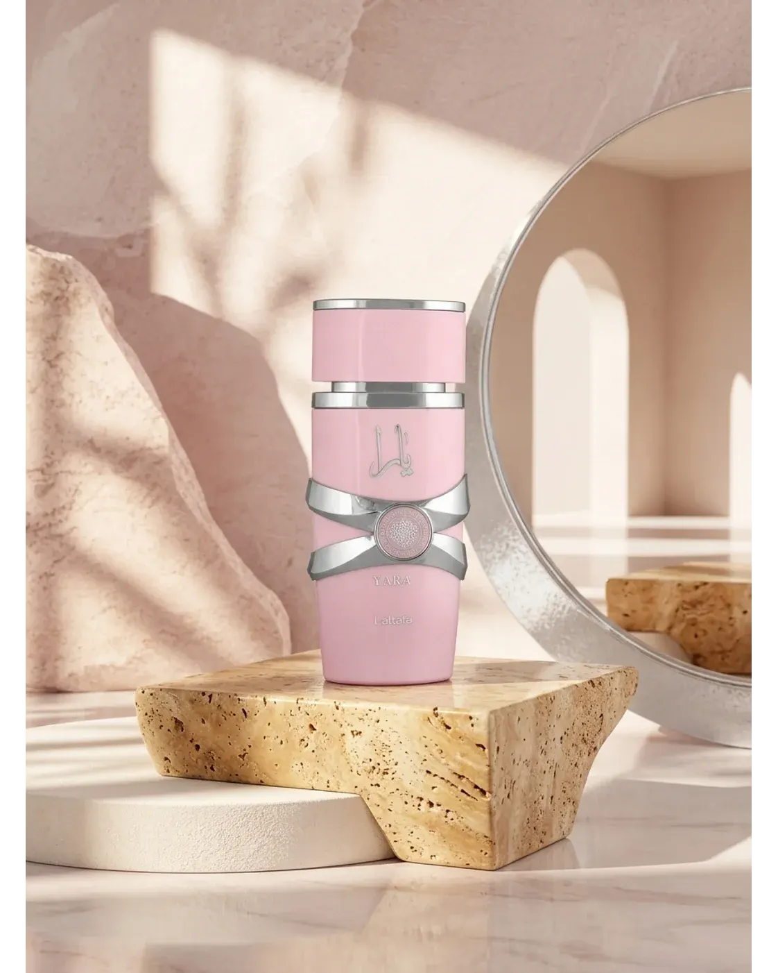 Lattafa Yara pink bottle on travertine pedestal in radiant light